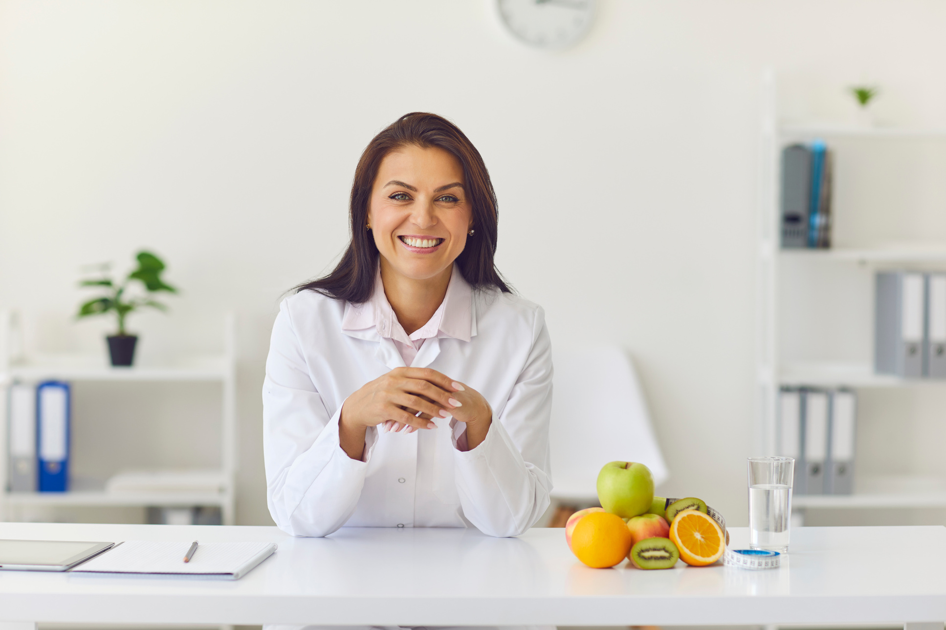 Happy Female Dietician Sitting at Her Desk in Office Looking at Camera and Smiling